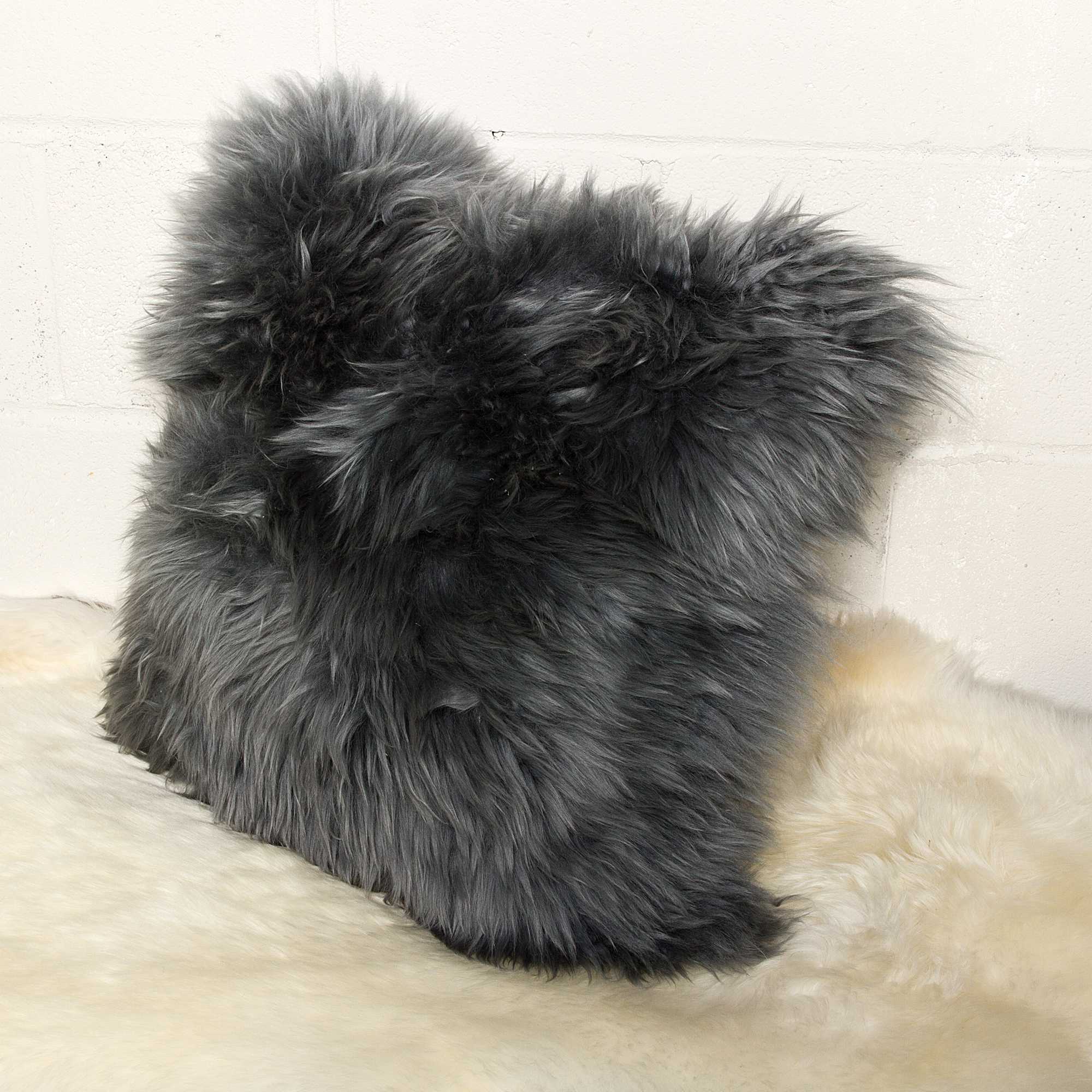 Fluffy gray pillow on a light beige surface with a neutral background