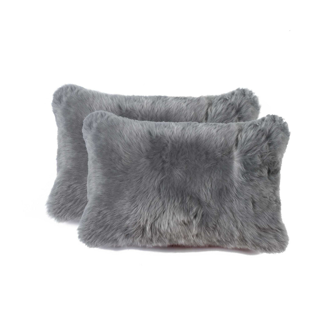 Two gray faux fur pillows on a white background