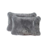 Two gray faux fur pillows on a white background
