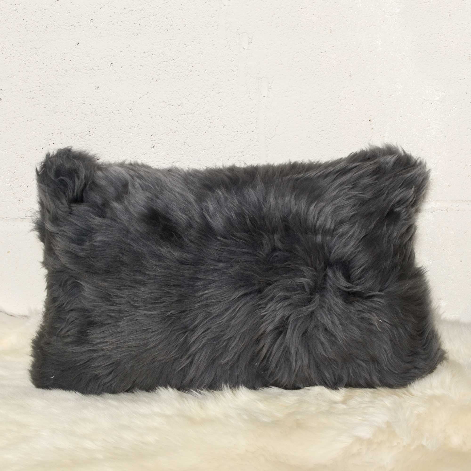 Gray fluffy pillow on a light beige surface with a neutral background