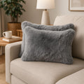Two fluffy gray pillows on a beige sofa in a cozy living room.
